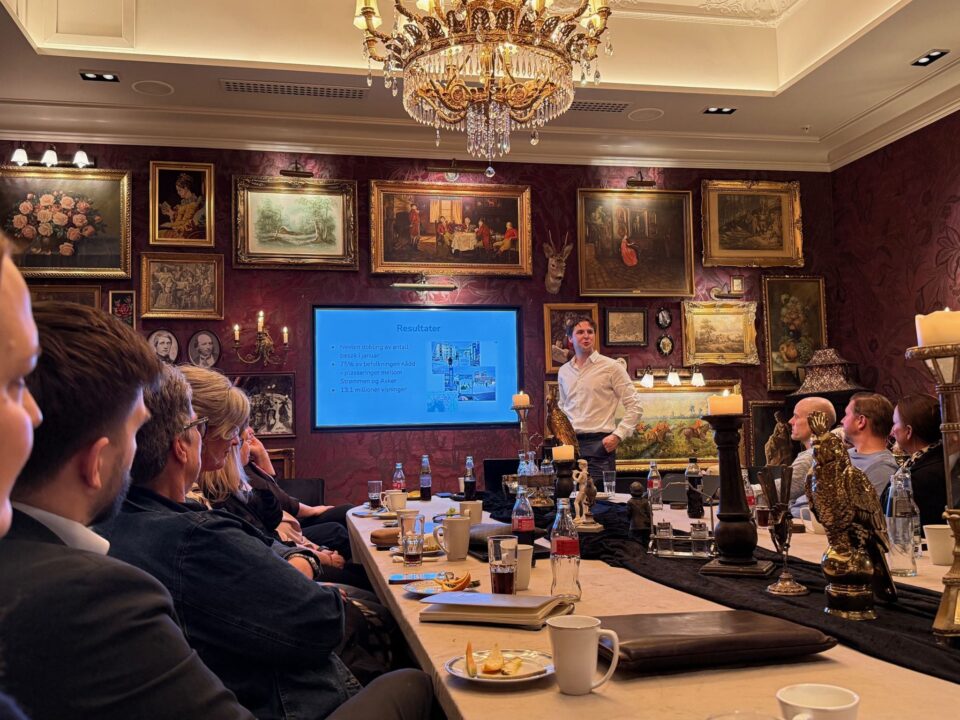Presentasjon for deltakere rundt et langbord i en salong med malerier under selskapsmøtet på Losby Gods